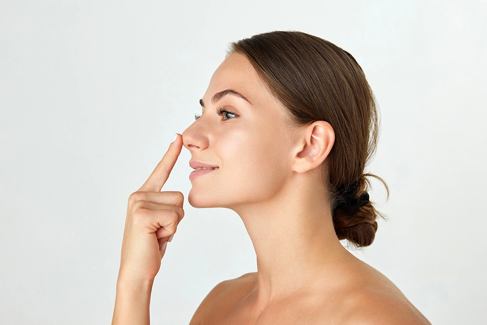 Side profile of woman touching her nose. Rhinoplasty concept